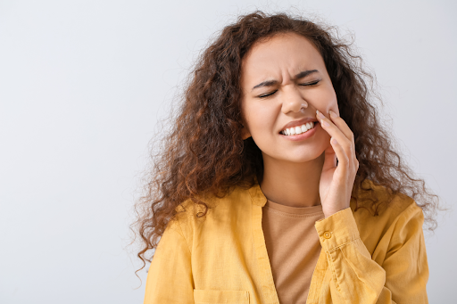 Woman with tooth pain holding her hand to her mouth.