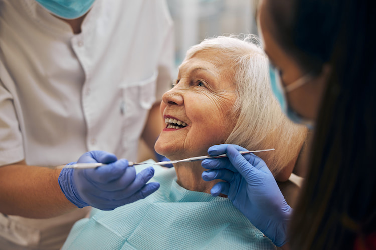 an old woman is using her government dental coverage for seniors in Canada by getting a dental checkup.
