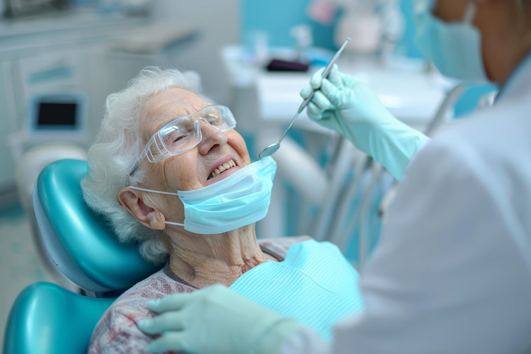 a dentist is examining his senior's patient's teeth.