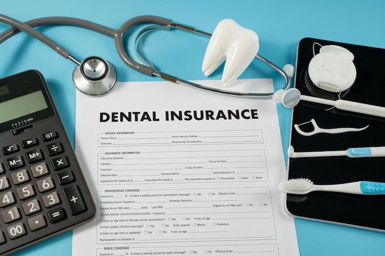 a dental insurance form with a calculator and dentistry tools next to it.